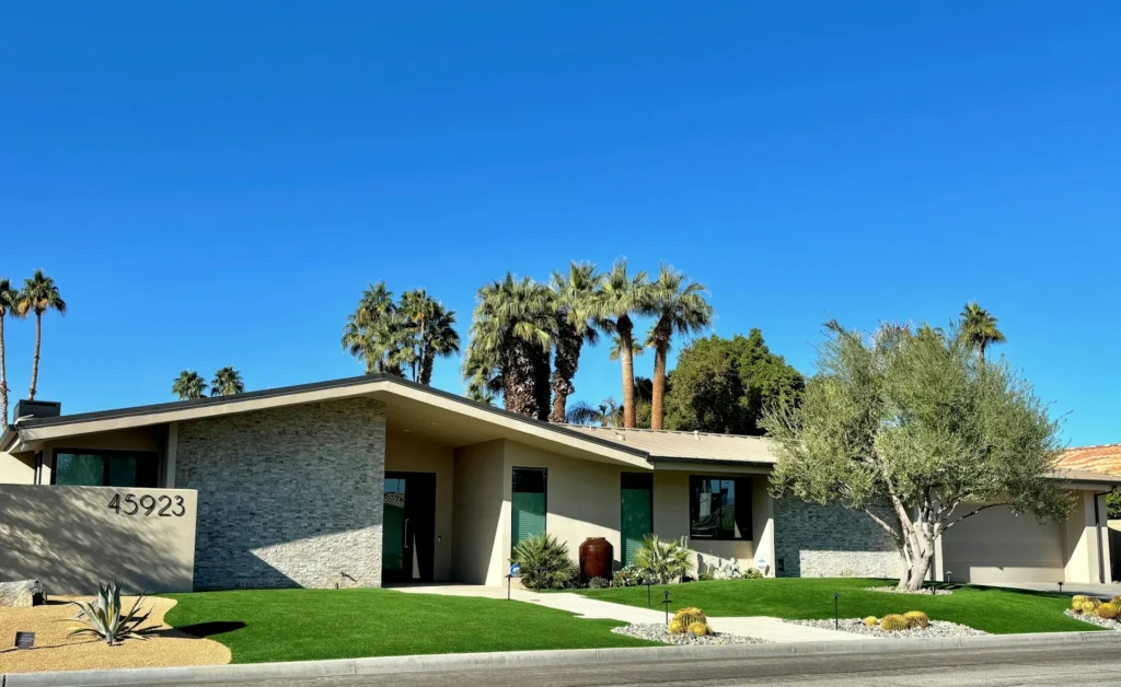 Single-story home with palm trees and blue sky.