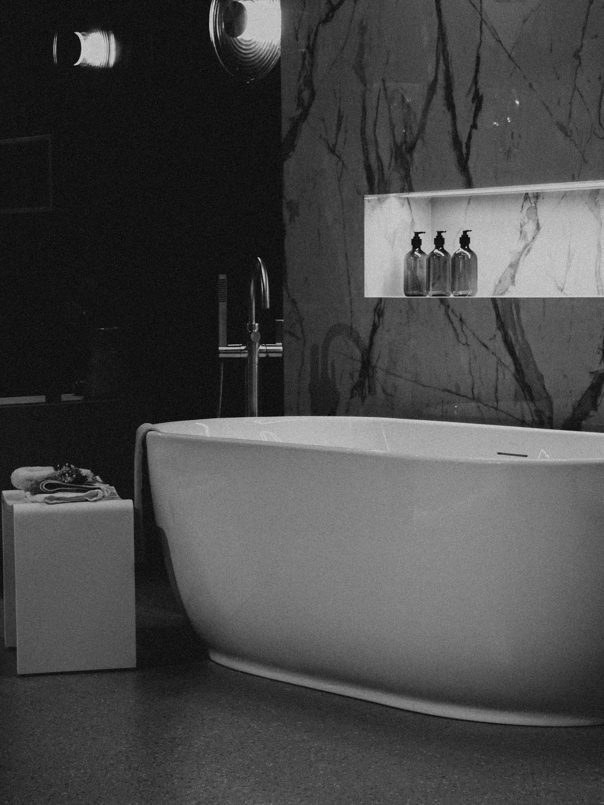 Dark bathroom with round mirror and marble walls.