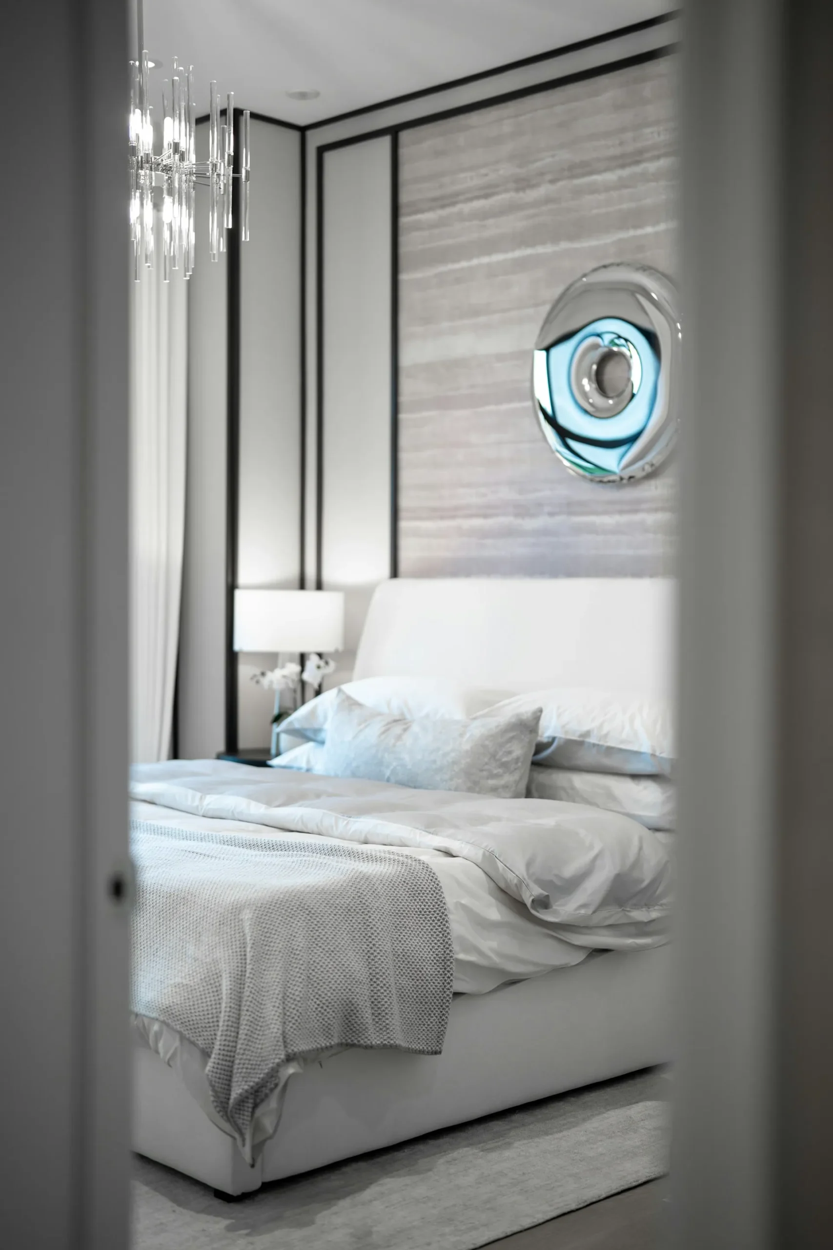 Modern bedroom with white bedding and wall art.