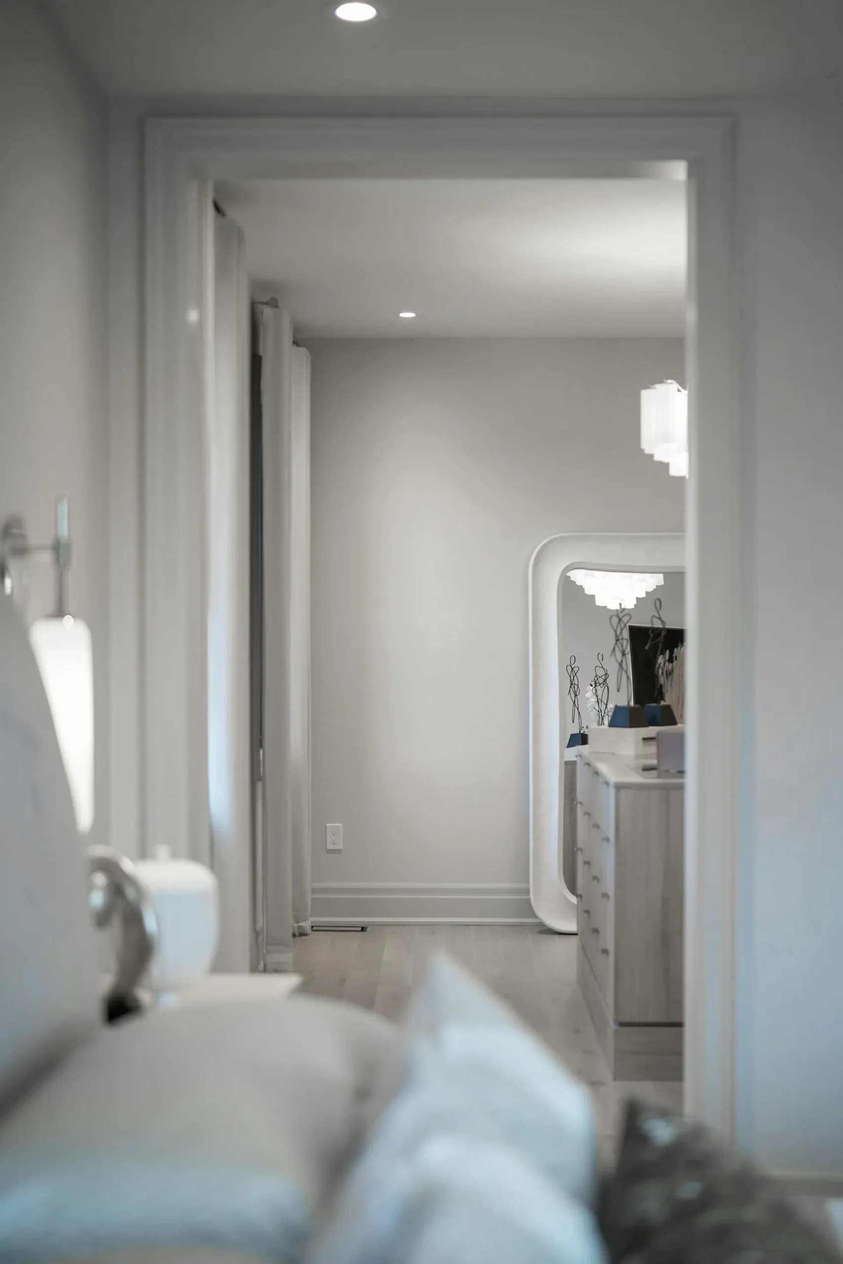 Soft modern bedroom with mirror, dresser, and neutral decor.