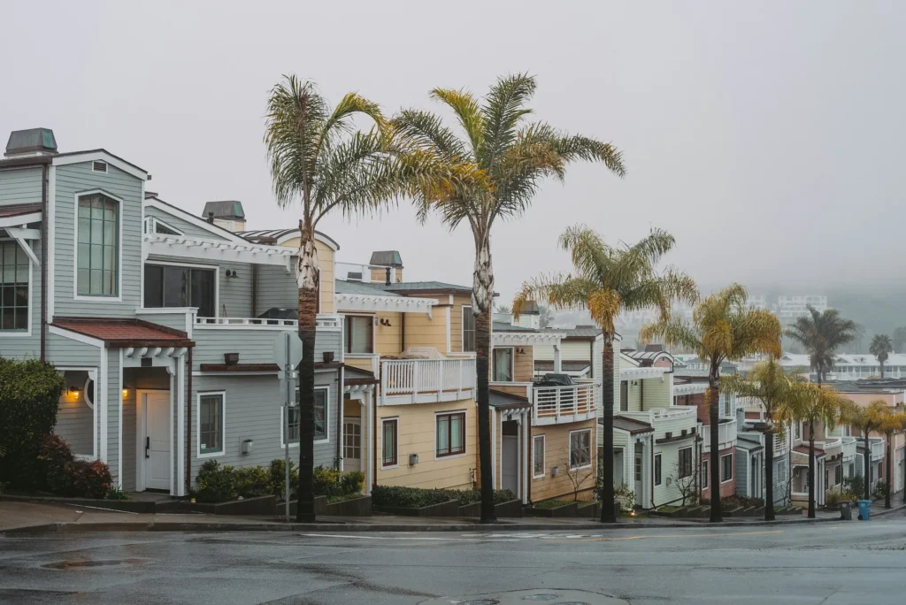 White building with palm trees and cloudy sky.